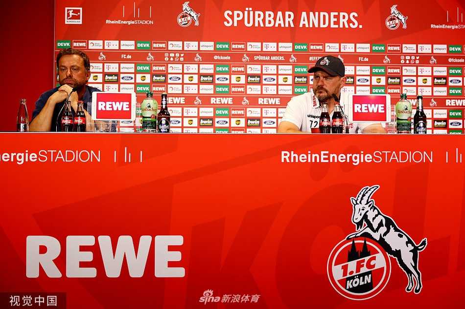 新任主帅斯特芬·鲍姆加特在发布会上展露标志性的爽朗笑容，眼神中透露出对未来的坚定与自信，身后的科隆队徽熠熠生辉。