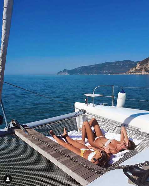 马蒂尔德与好友在繁华都市的天台酒吧俯瞰璀璨夜景，霓虹灯光映衬着她精致的妆容和自信的笑容