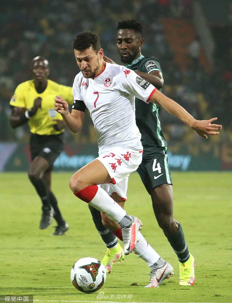 一位突尼斯小球迷脸上画着国旗彩绘，手持围巾，眼中充满期待与激情地凝望着赛场。