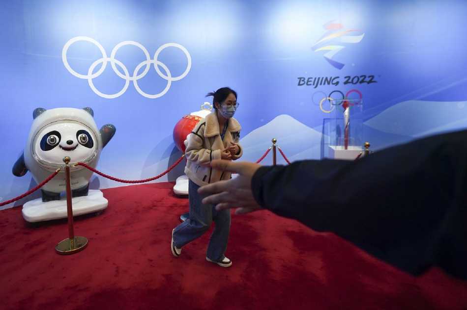 鸟巢内的冬奥主题展区宛如一片蓝白色的海洋，几位身着蓝色志愿者服装的“奥运人”簇拥在一起，他们高高举起记录着自己荣耀时刻的冬奥会工作证件，围绕在可爱的冰墩墩和雪容融周围，快门声响起，定格下这灿烂的笑脸。