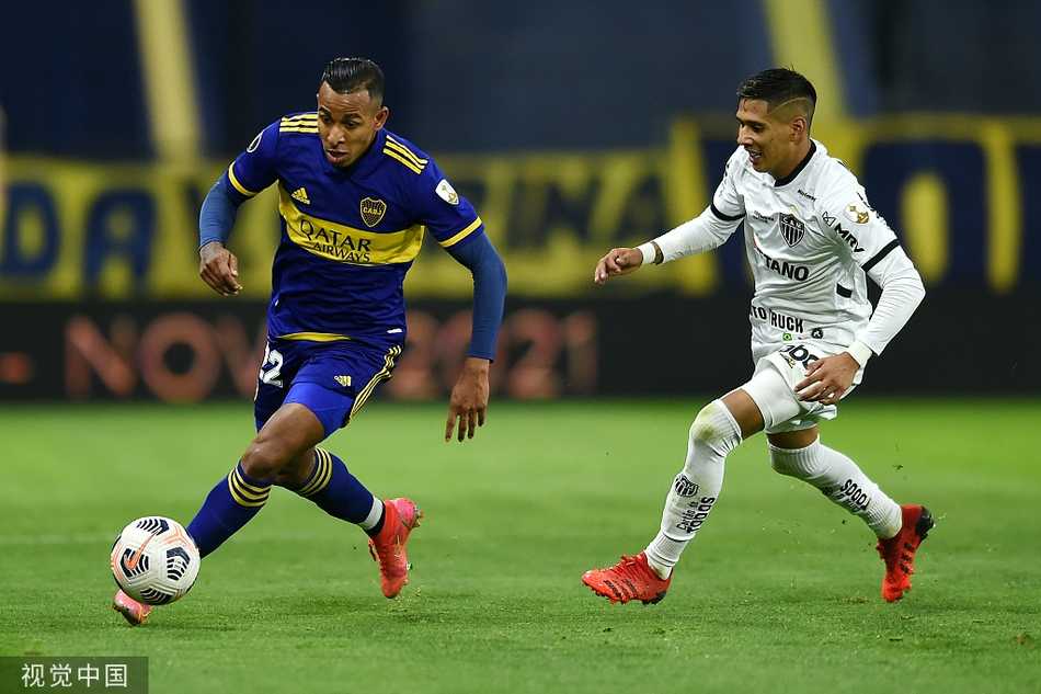 身穿蓝色球衣的博卡青年球员在糖果盒球场标志性的黄色阶梯看台前，正起脚大力射门，整个球场的氛围仿佛凝固在这一瞬间