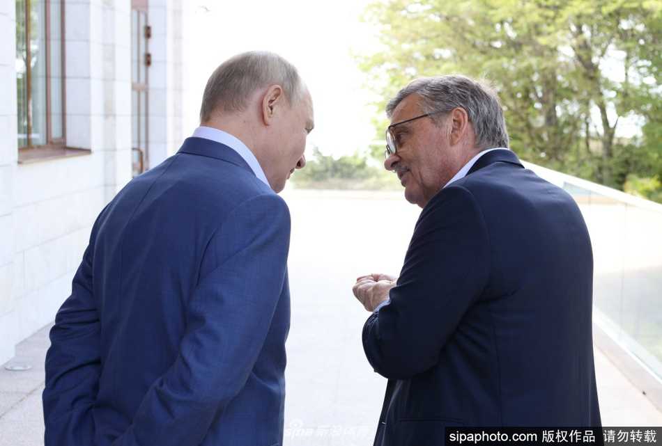 在另一个瞬间，普京总统展现出了轻松的倾听姿态。他微微侧头，眼神中透露出对法塞尔主席关于俄罗斯冰球发展看法的浓厚兴趣。窗外柔和的光线勾勒出人物的轮廓，使得这张照片充满了外交场合中少有的亲和力。