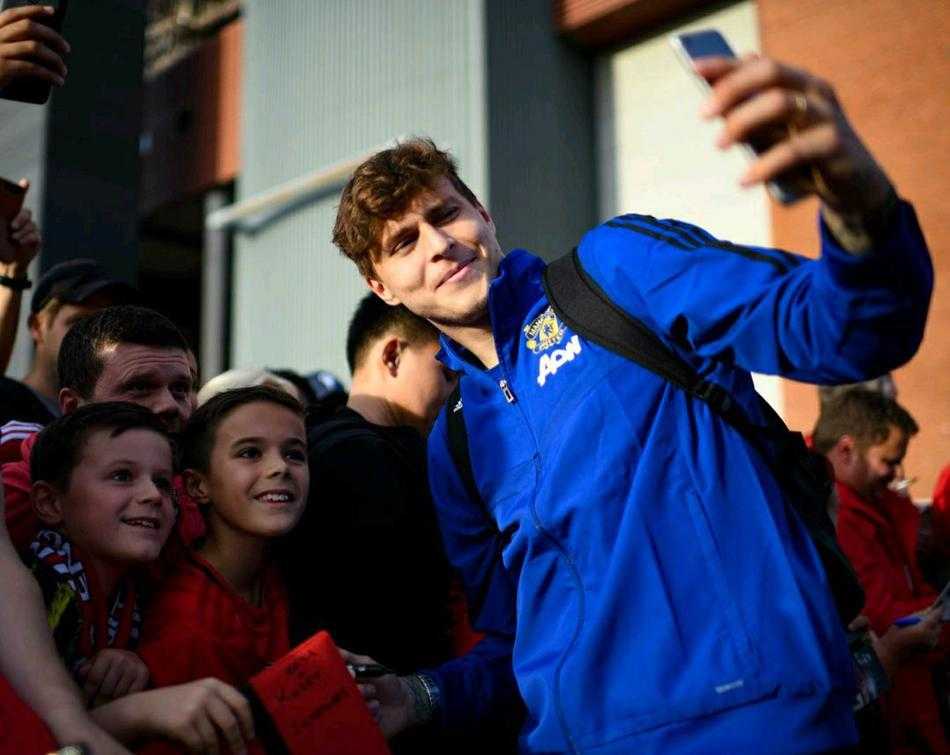 阳光洒在老特拉福德球场的看台上，索尔斯克亚和曼联球员们站成一排，与面前密密麻麻的球迷们进行大合影，大家比出胜利的手势，这一刻的笑容属于整个曼联大家庭