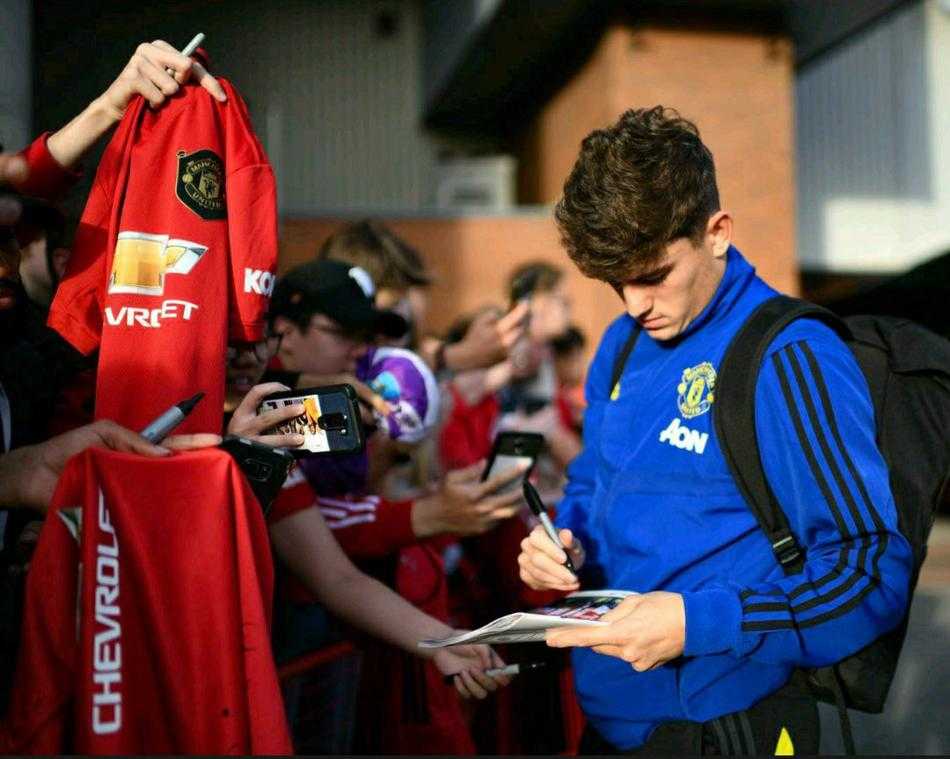 镜头拉近，索尔斯克亚被一群兴奋的曼联球迷簇拥着，他亲切地搂着一位老球迷的肩膀，仿佛是在与多年老友叙旧，球员们在身后也纷纷与球迷击掌互动