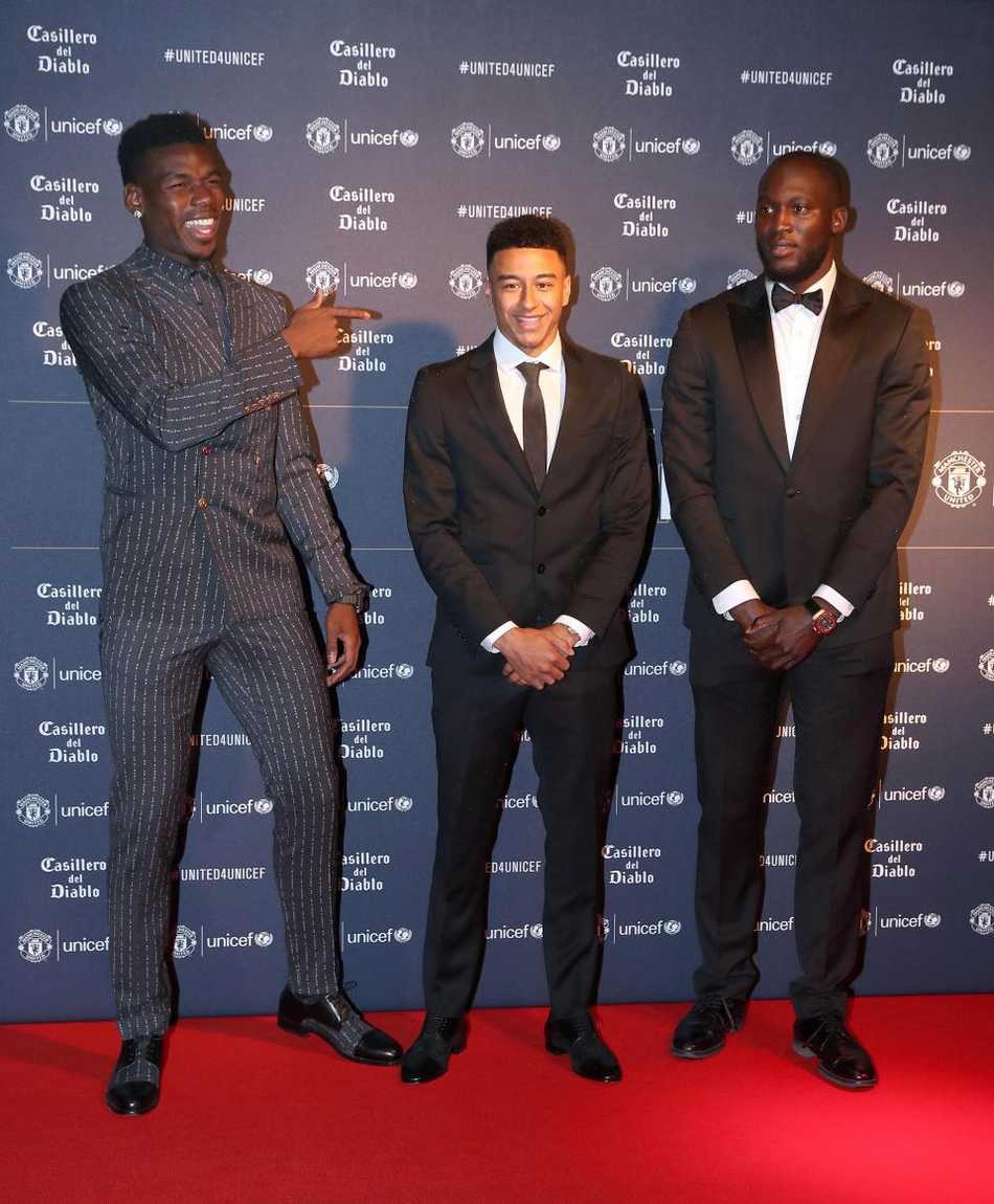 博格巴在晚宴内场与卢卡库相谈甚欢，两人手中都拿着写有祝福话语的卡片，身后是布置温馨的联合国儿童基金会背景板，气氛轻松愉快。