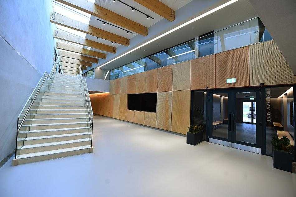 宽敞明亮的球员更衣室内，红黑基调的设计充满科技感与力量感，每个专属柜位上整齐摆放着装备，仿佛在静待着新一代传奇的主人。