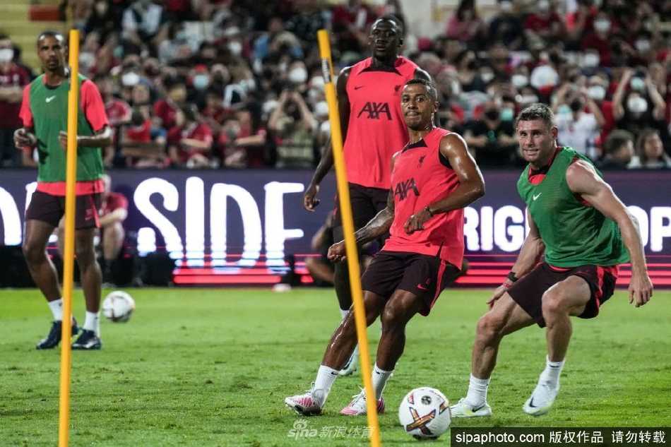 训练间隙，萨拉赫与一位年轻队友并肩而坐，交流着技术动作，阳光洒在草地上，画面显得格外温暖与和谐。