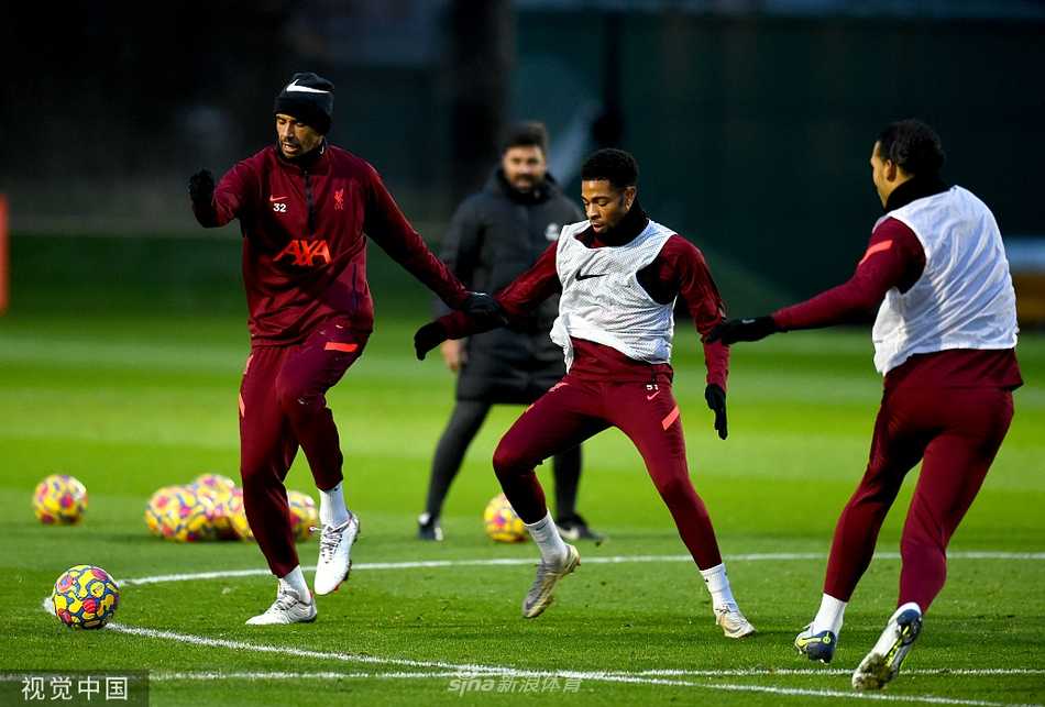 利物浦队员在进行激烈的分组对抗赛，一名红衣球员正带球突破，两名队友在侧后方协防，场面充满了实战的紧张感。