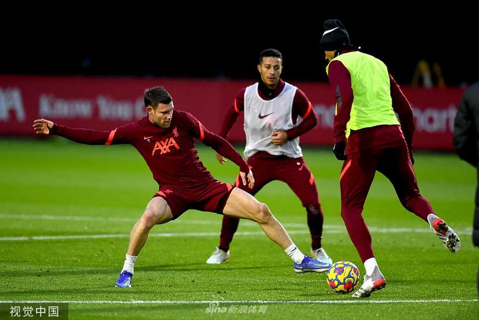 萨拉赫与蒂亚戈在绿茵场中央相对而立，两人笑容灿烂，正伸出右脚进行轻松的‘对脚’游戏，阳光将他们的身影拉长，画面充满友爱的竞技趣味。