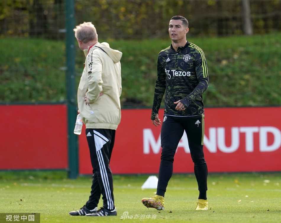 曼联主教练埃里克·滕哈格站在训练场边，双臂交叉，目光如炬地观察着场上球员的每一次跑动与传球。