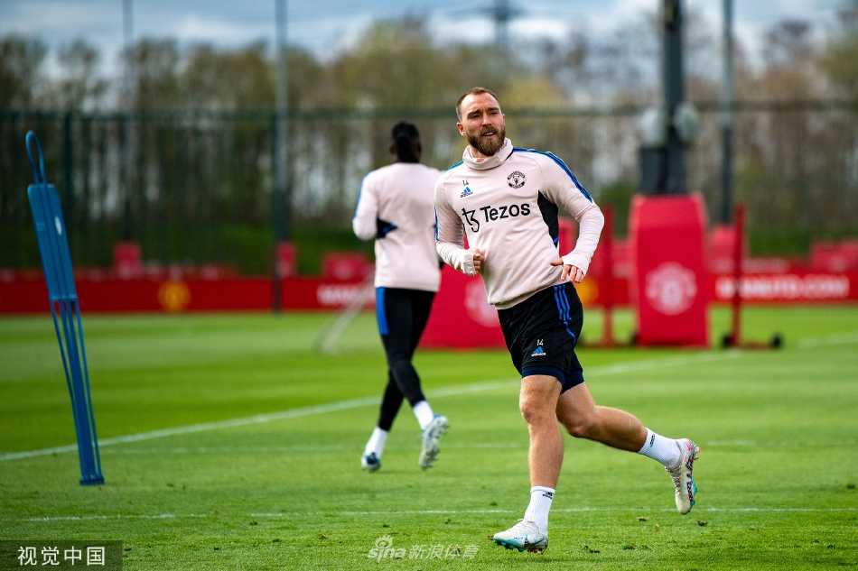 曼联主教练埃里克·滕哈格在训练场边专注指导，手持战术板，目光如炬地审视场上球员的每一次跑动与配合。