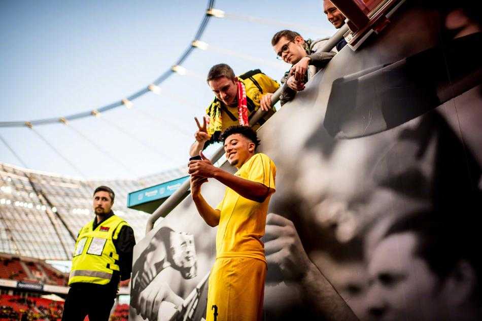 看台上，一位年轻女球迷脸上画着油彩，眼中闪烁着对足球最纯粹的热爱与光芒