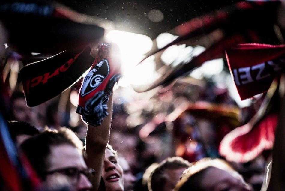 看台上人山人海，球迷们挥舞着旗帜和围巾，汇成一片彩色的海洋，声浪仿佛要冲破云霄