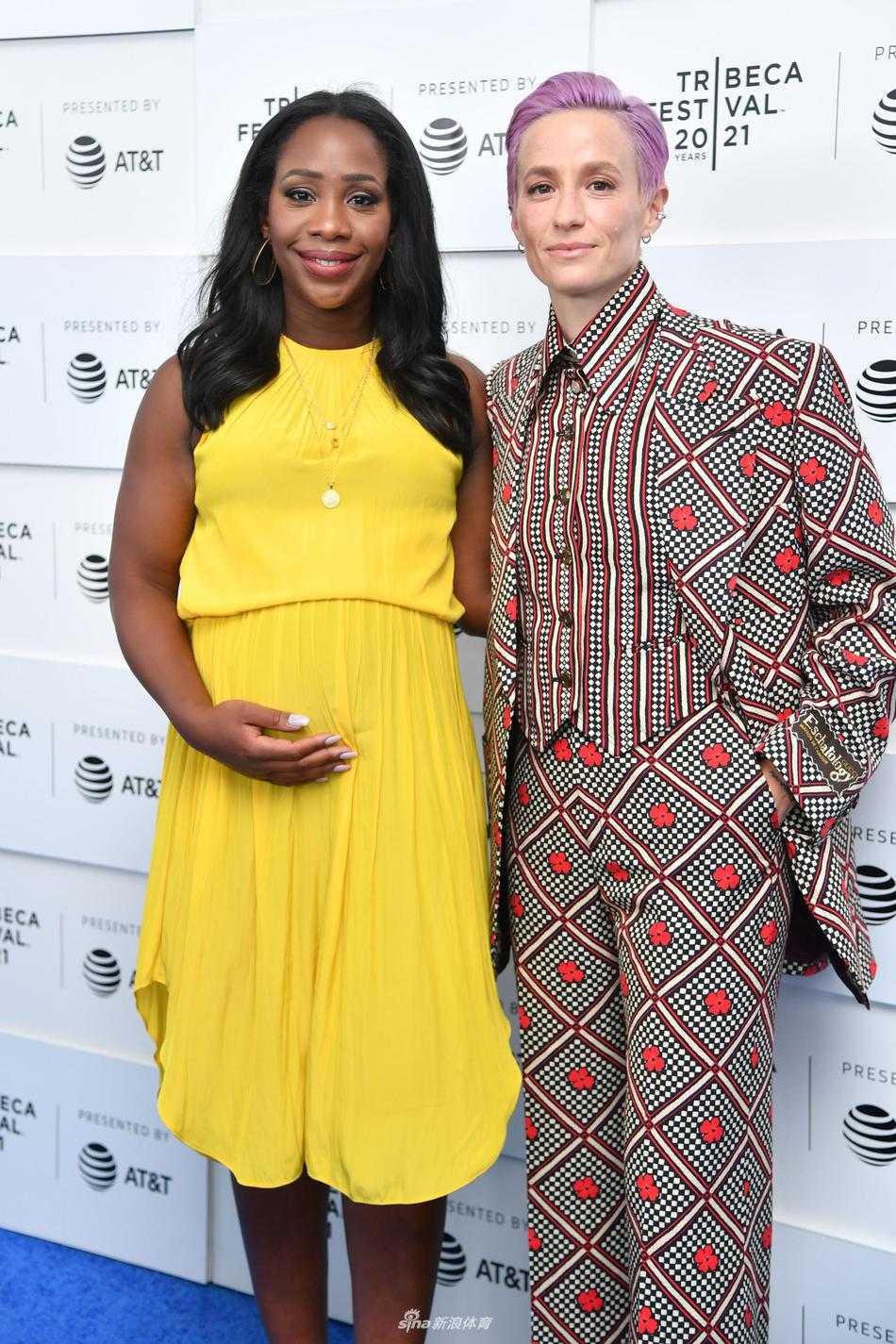 镜头捕捉到了梅根·拉皮诺埃在活动现场与友人交谈的瞬间。她侧身倾听，嘴角带着浅浅的笑意，花色西装的垫肩设计让她显得格外挺拔，柔和的灯光洒在她身上，勾勒出一位成熟女性的优雅轮廓。