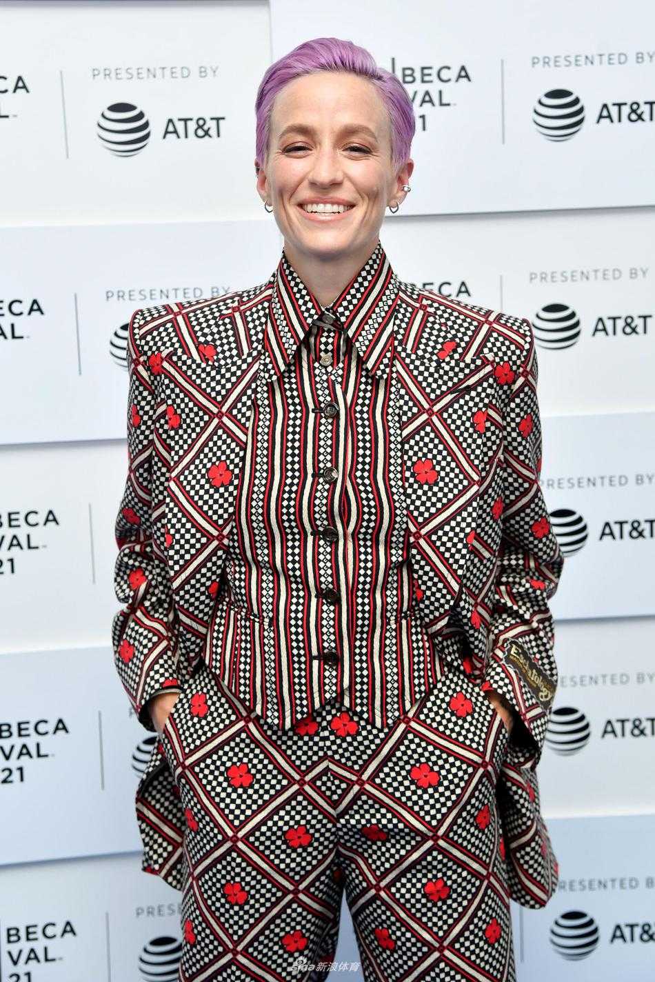 梅根·拉皮诺埃独自站立在背景板前，目光坚定地望向远方。花色西装的细节在闪光灯下清晰可见，华丽的印花与她从容强大的气场相得益彰，仿佛在无声地诉说着一位斗士的荣耀与坚持。